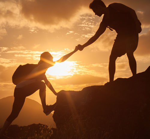 person helping another climb up a rock